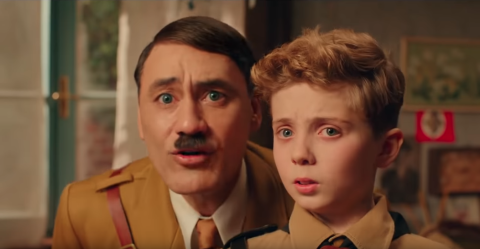 A frame from the movie “Jojo Rabbit” – a 10uo boy stands next to his imaginary friend, Hitler